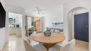 Een moderne eetruimte met een ronde houten tafel, beklede stoelen en een plafondventilator.