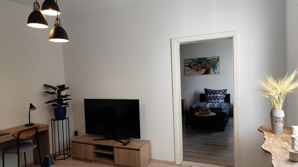 Uma sala de estar moderna com uma escrivaninha de madeira, uma televisão e um espelho grande.
