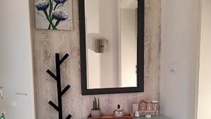 Casa de banho com parede de madeira, espelho, uma pequena mesa com objetos decorativos e um tapete preto.