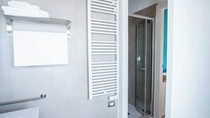 Un baño moderno con ducha de vidrio, un perchero para toallas y un estante para toallas.