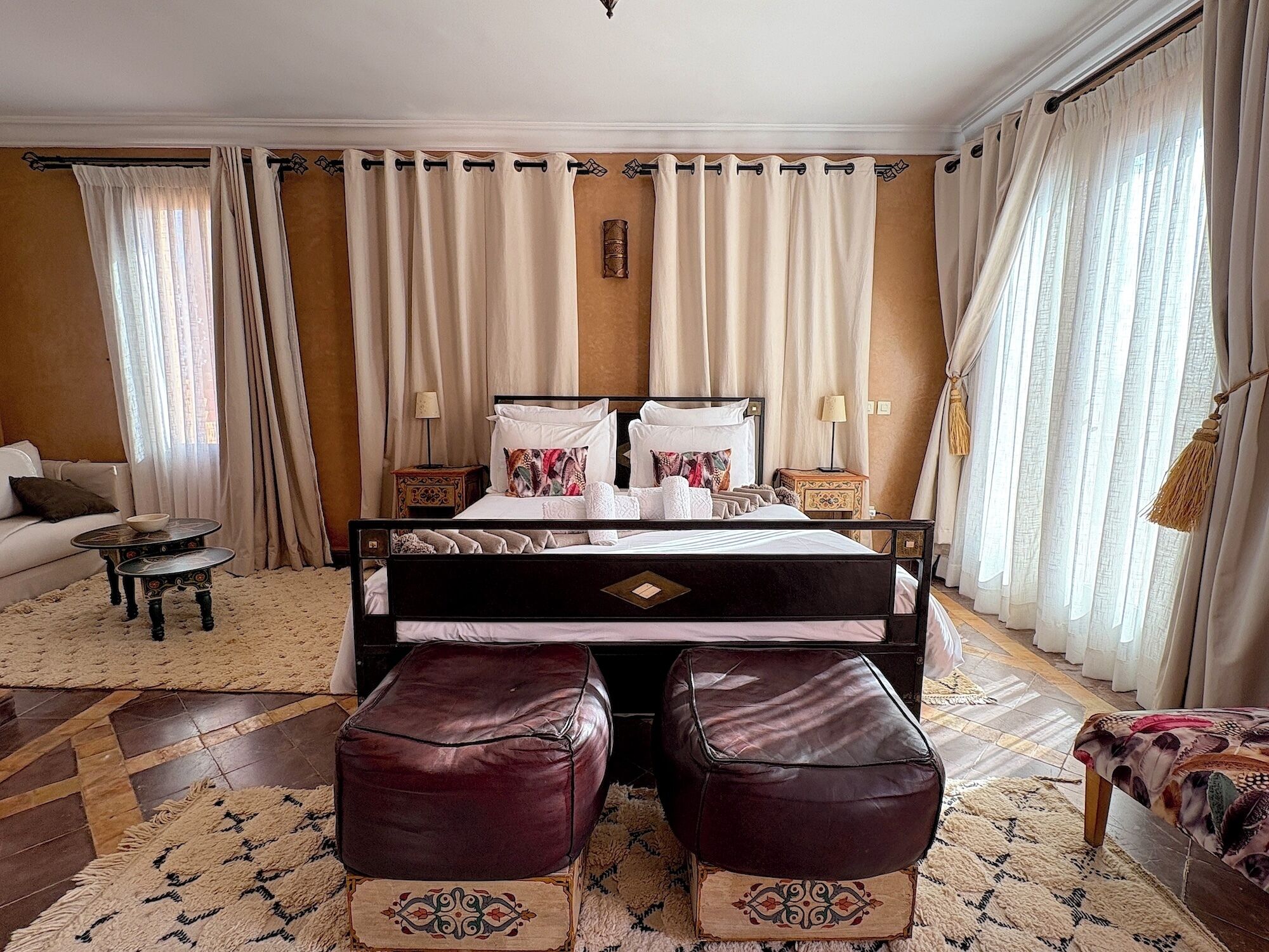 A bedroom with a bed, two nightstands, a sofa, and a patterned rug.
