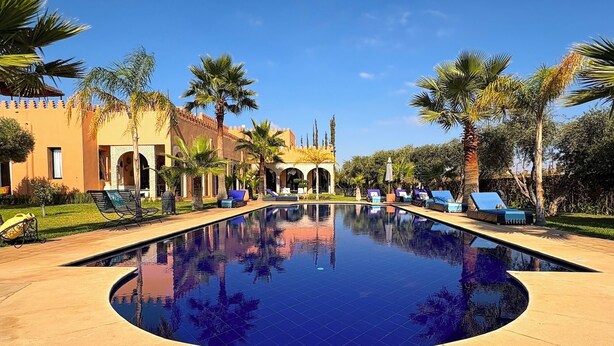 A pool area with lounge chairs and palm trees.