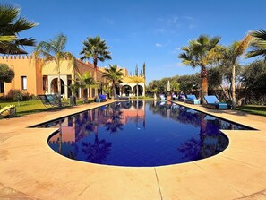 A pool area with lounge chairs and palm trees. - Palais Khemia (Marrakech)
