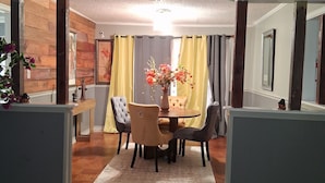 Un coin repas avec une table ronde, des chaises et un vase de fleurs.