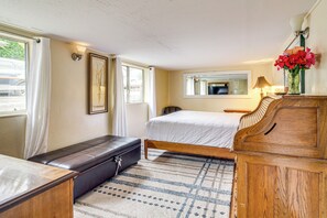 A bedroom with a bed, a wooden dresser, a bench, a window with curtains, a mirror, and a lamp. - Quaint Coos Bay Escape, 2 Mi to Downtown (Coos Bay)