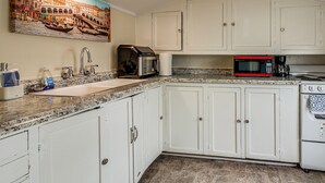 A kitchen with white cabinets, a granite countertop, a sink, a coffee maker, a microwave, and an oven. - Quaint Coos Bay Escape, 2 Mi to Downtown (Coos Bay)