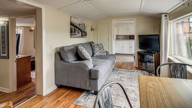 A compact living space with a grey sofa, a television, and a dining table. - Quaint Coos Bay Escape, 2 Mi to Downtown (Coos Bay)