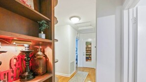 Un pasillo con estanterías de madera, un tapete y una puerta que da a otra habitación.