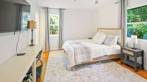 Un dormitorio con cama, mesita de noche, escritorio y ventilador de techo.