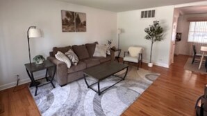 A living room with a brown sofa, a coffee table, a side table, and a floor lamp. - Tranquil 3-bedroom house with AC in Elk Grove Village (Elk Grove Village)
