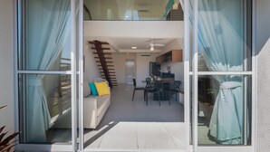 Un apartament modern amb un balcó, una zona de menjador i una escala que porta a un nivell superior.