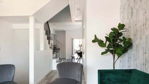 A modern living room with a grey armchair, a green sofa, and a staircase leading to an upper floor. - Experience Luxury 4BR Townhouse, Sleeps 8 with Parking (Los Angeles)