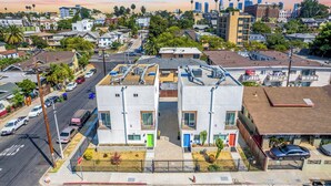 Un immeuble résidentiel à plusieurs étages doté d’une cour intérieure, d’un parking et donnant sur la rue, avec des voitures et d’autres immeubles en arrière-plan.