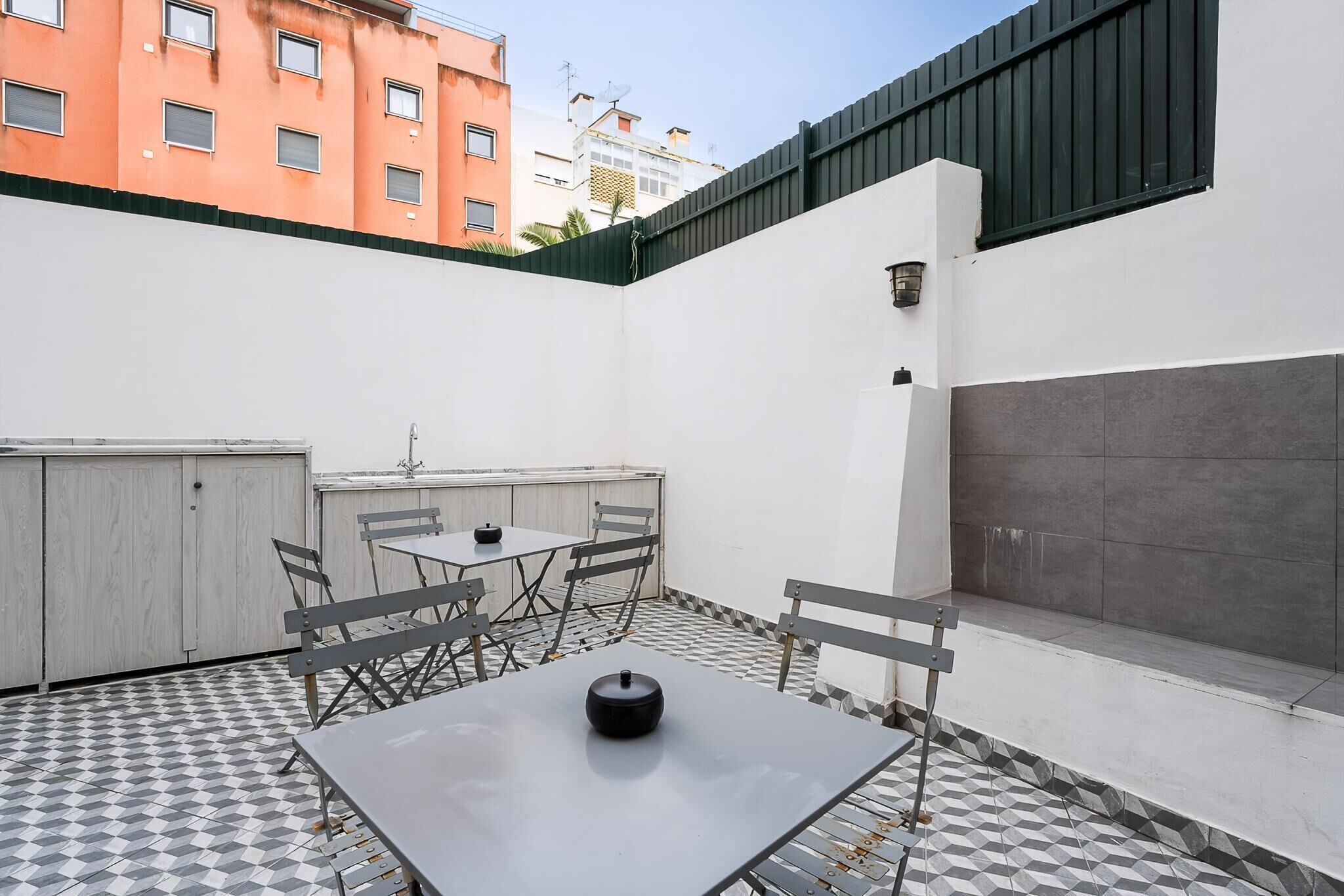 Um terraço no telhado com mesa, cadeiras e uma mesinha com tampa.