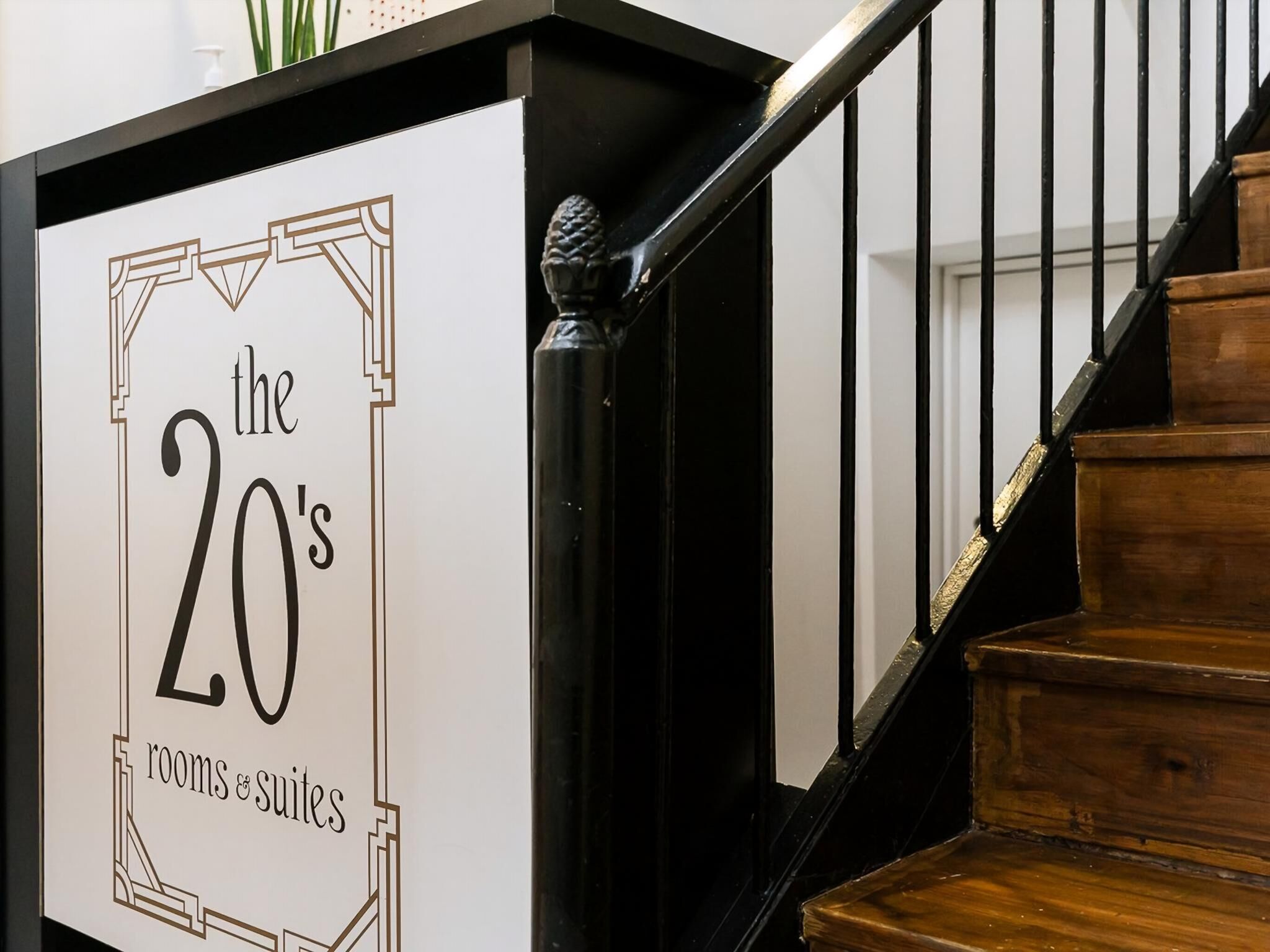 Een trap met een bord waarop 'de jaren twintig kamers & suites' staat.