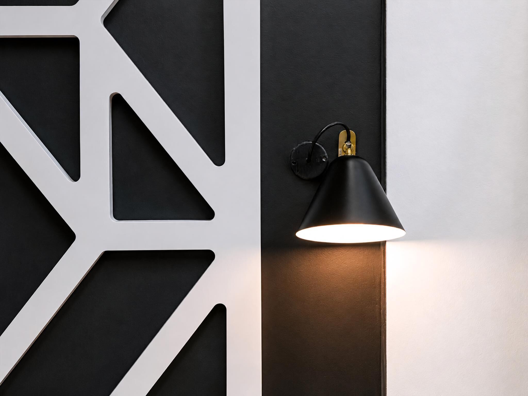 A wall with geometric patterns and a wall-mounted lamp.