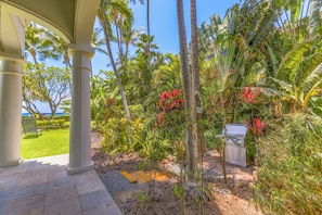 A covered outdoor area with palm trees, a grill, and a view of the ocean. - Stay Beachfront, Explore Maui’s Outdoors 629 LS (Lahaina)