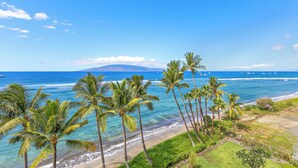 A beach with palm trees, clear blue water, and distant mountains. - Stay Beachfront, Explore Maui’s Outdoors 629 LS (Lahaina)