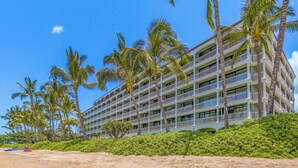 A multi-story hotel with balconies, surrounded by palm trees and a sandy beach. - Stay Beachfront, Explore Maui’s Outdoors 629 LS (Lahaina)