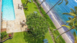 An aerial view of a resort with a swimming pool, lounge chairs, and a beach with palm trees. - Stay Beachfront, Explore Maui’s Outdoors 629 LS (Lahaina)