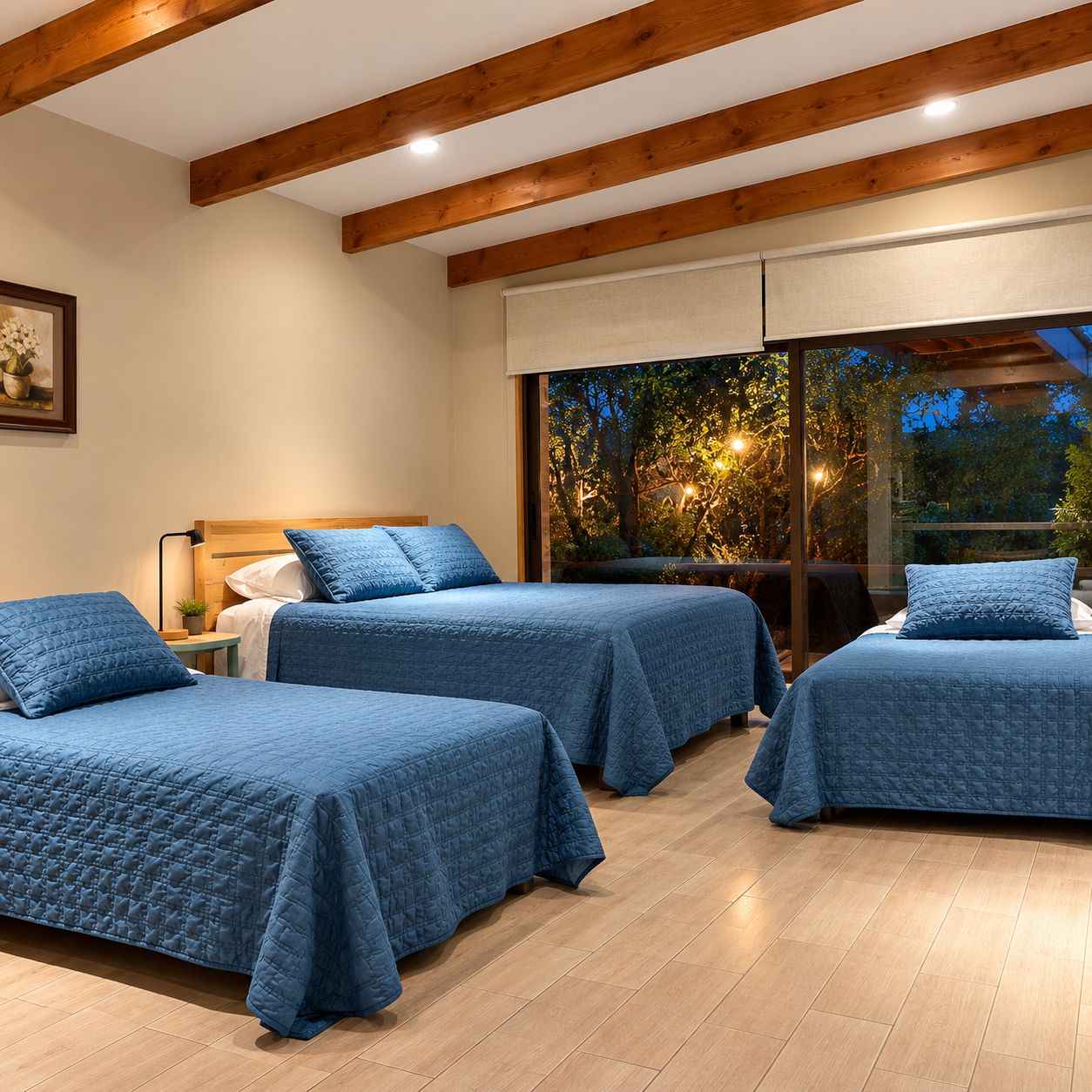 A room with three beds, wooden beams on the ceiling, and a large window with a view of trees.