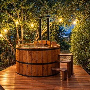 Un bain à remous en bois de forme circulaire, entouré d’une terrasse en bois et de bancs.