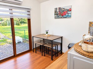 Une cuisine moderne avec une table en bois, une plante en pot et un tableau représentant un paysage urbain accroché au mur.