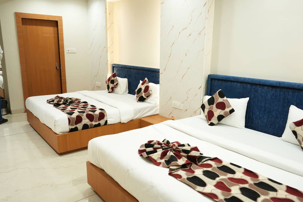 A hotel room with two beds, each with a blue headboard, white bedding, and patterned throw blankets.