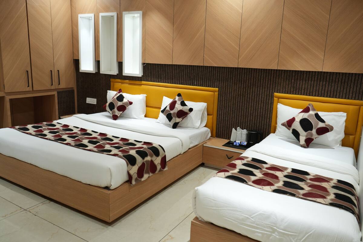 A hotel room with two beds, wooden paneling, a mirror, and a bedside table with a lamp.