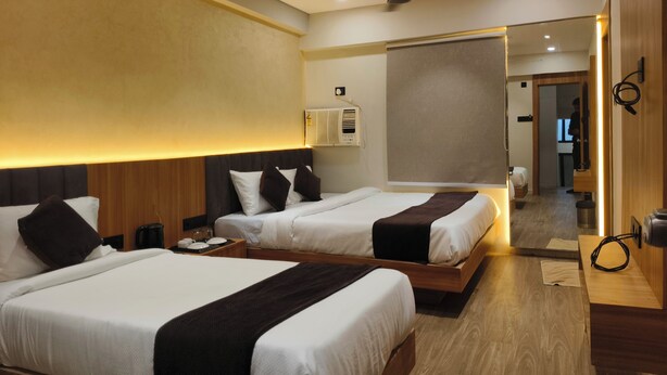 A hotel room with two beds, a ceiling fan, an air conditioning unit, and a large mirror. - The samsara Hotel by Satyug (Ujjain)