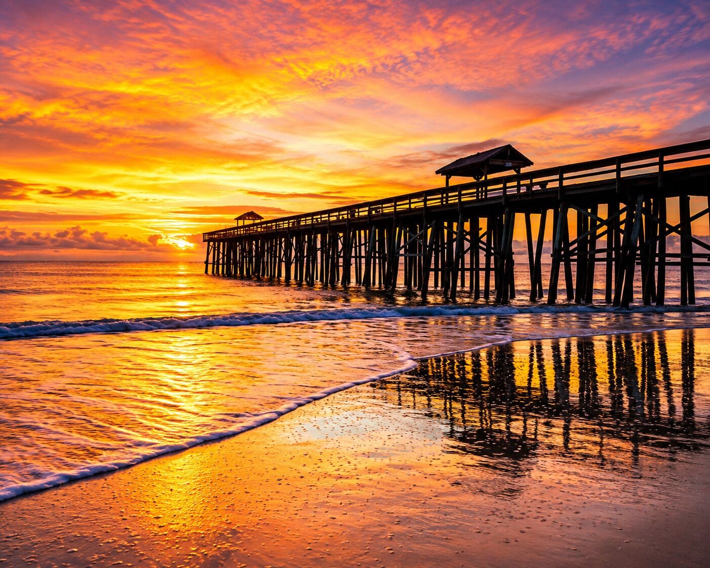 A pier extending into the ocean with a sunset in the background.