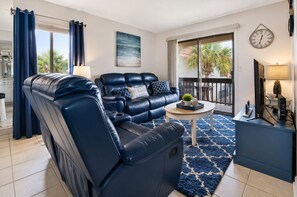 A modern living room with a leather sofa, a coffee table, and a TV on a stand.