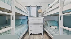 A bunk bed room with a central dresser, a lamp, and a sign indicating a lift.