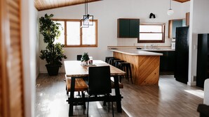 Una cocina moderna con armarios de madera, una isla central y un comedor con mesa y sillas de madera.