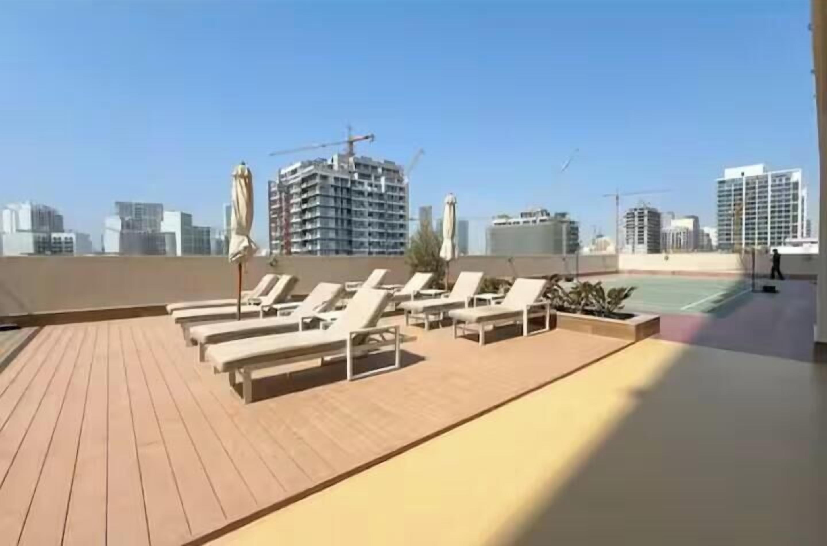 Une terrasse sur le toit avec des chaises longues, un court de tennis et une vue sur le panorama urbain.