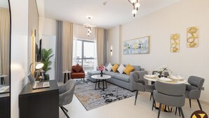 Ein modernes Wohnzimmer mit grauem Sofa, Couchtisch und Essbereich mit Stühlen und Tisch, gedeckt für eine Mahlzeit.