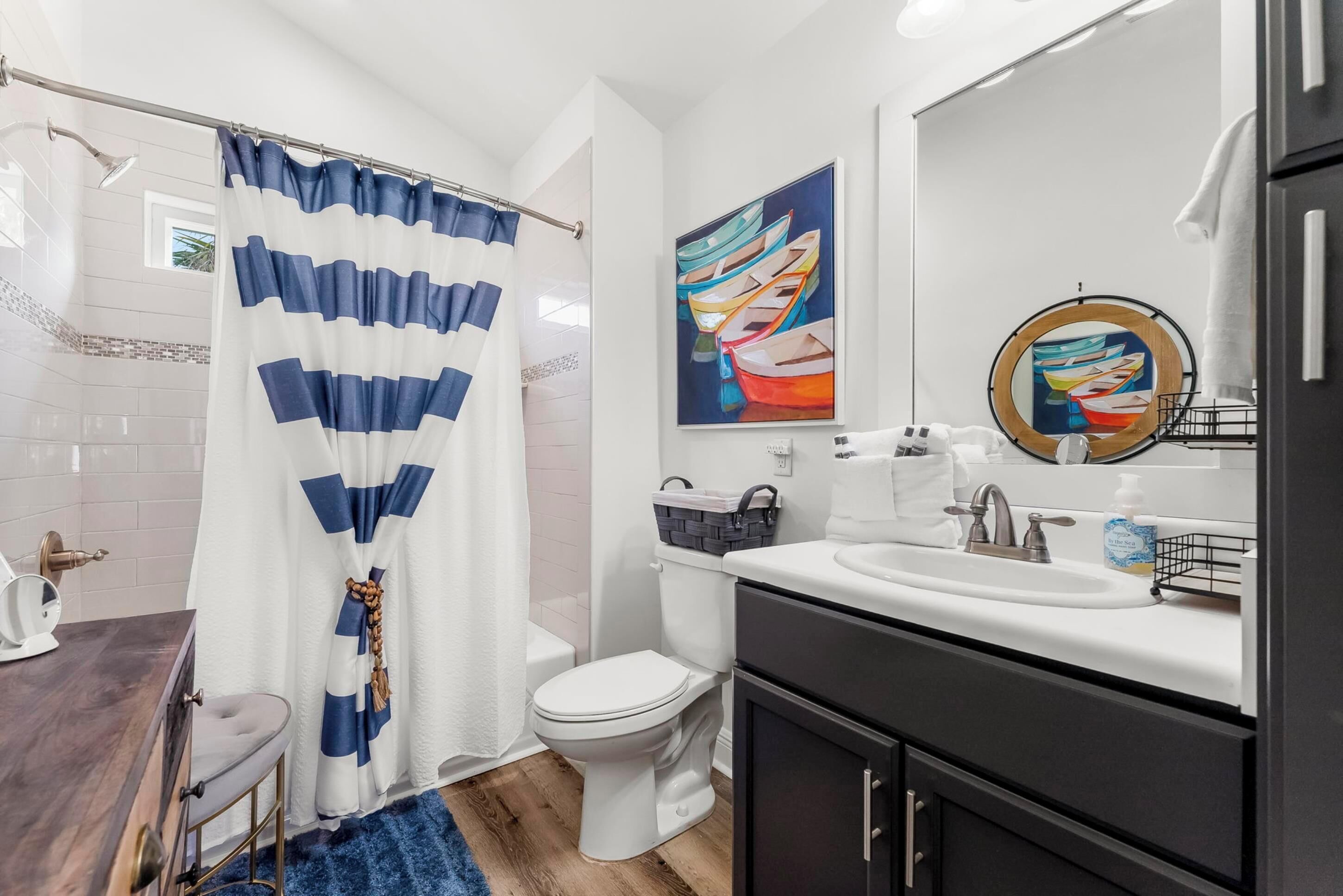 Un bany modern amb un vàter blanc, un lavabo amb mirall i un teló de dutxa.