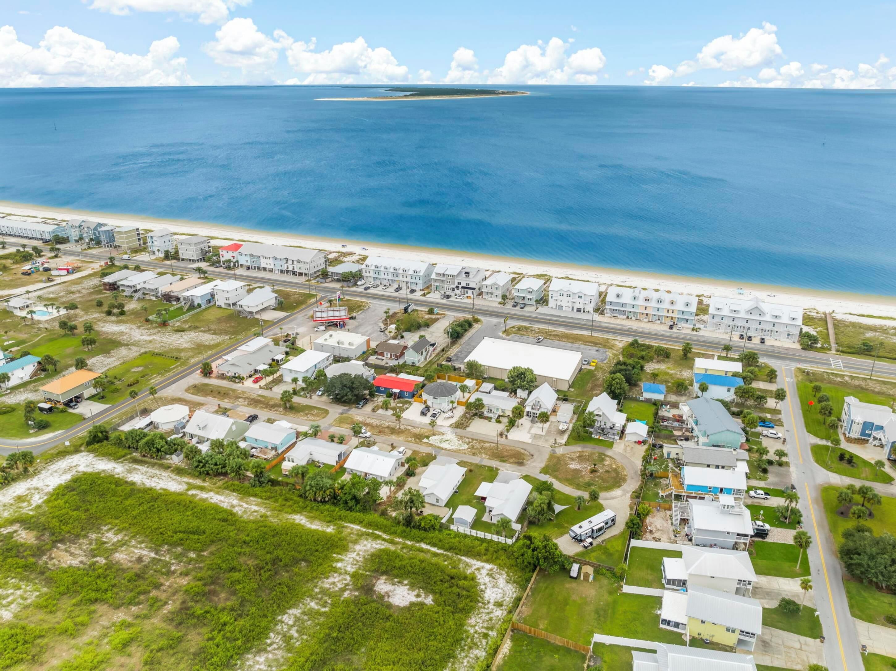 An aerial view of a coastal residential area with houses, roads, and a beach.