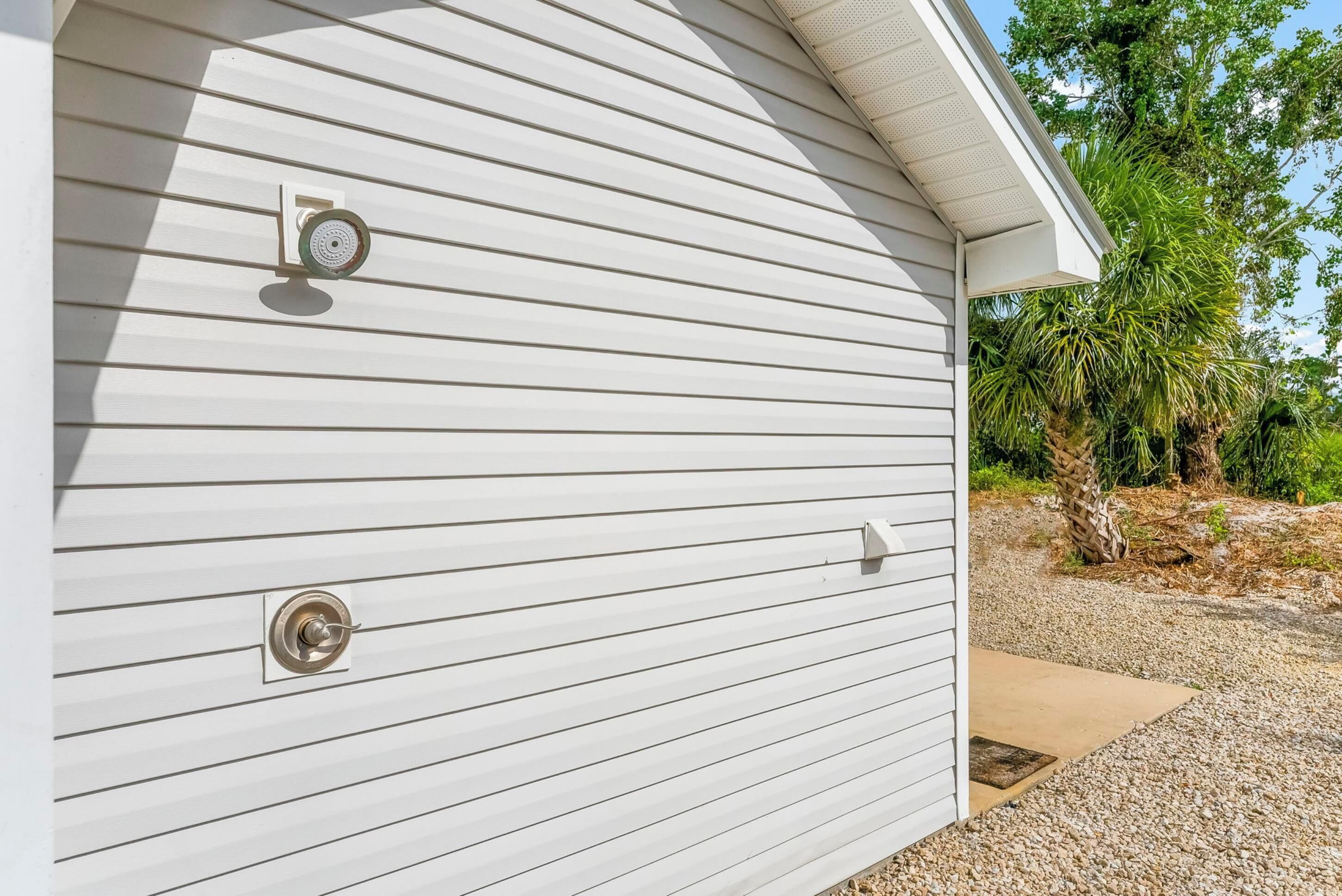 A white building with horizontal siding, a metal door with a keyhole, and a small window with a security camera.