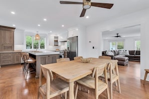 A spacious kitchen with a central island, wooden dining table, and chairs. - Private Pool, Game Room & Tons of Fun in Harwich RPAM118 (Harwich)