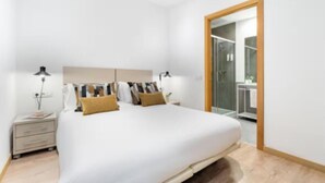 A modern bedroom with a large bed, bedside tables, and a glass shower area.