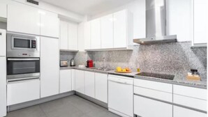 A modern kitchen with white cabinets, stainless steel appliances, and a granite countertop.