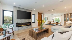 Una sala de estar moderna con chimenea, televisor de pantalla plana y comedor con mesa y sillas.