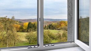 Una ventana con vistas a un paisaje que incluye árboles y colinas.