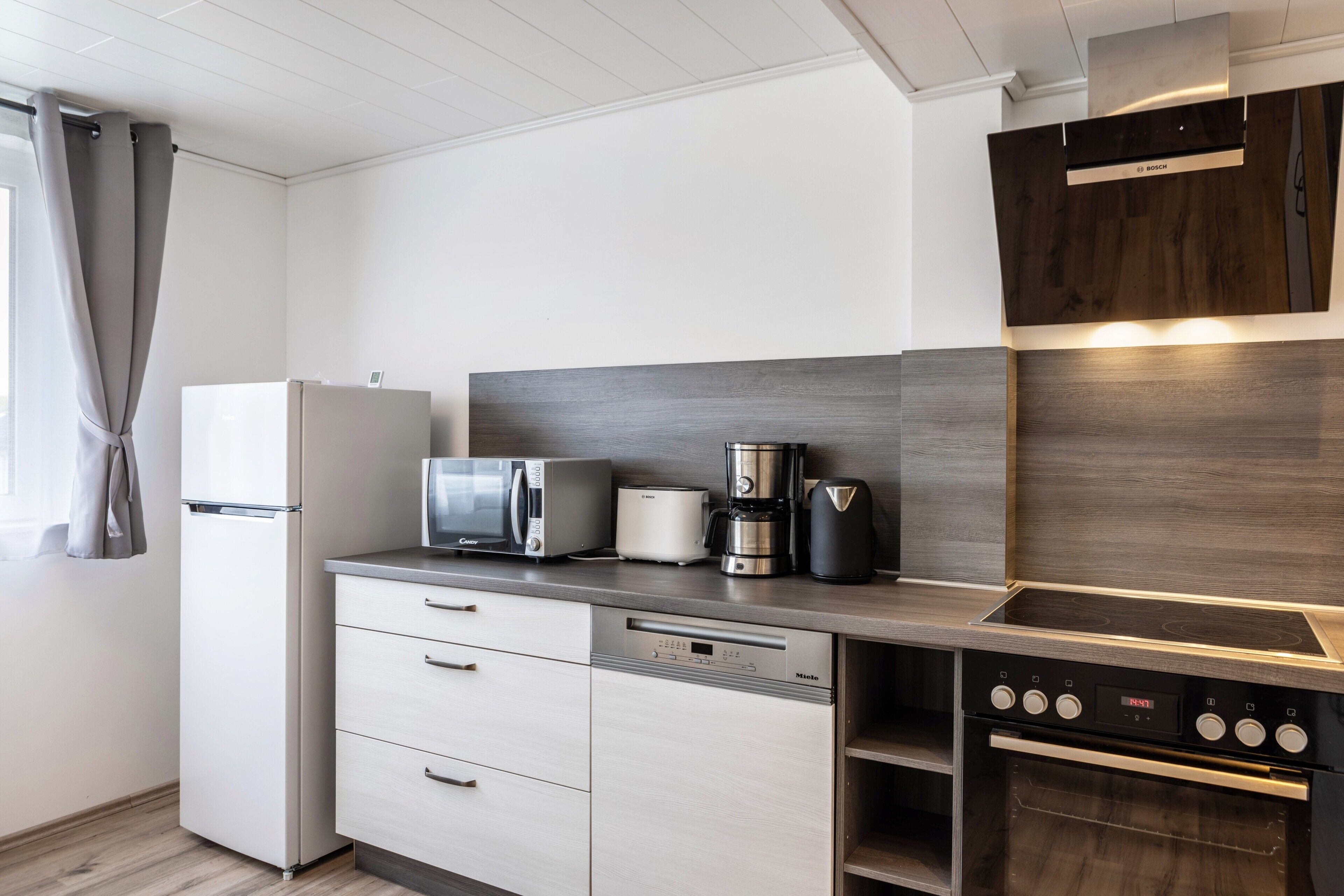 Una cocina moderna con microondas, cafetera y horno integrados.
