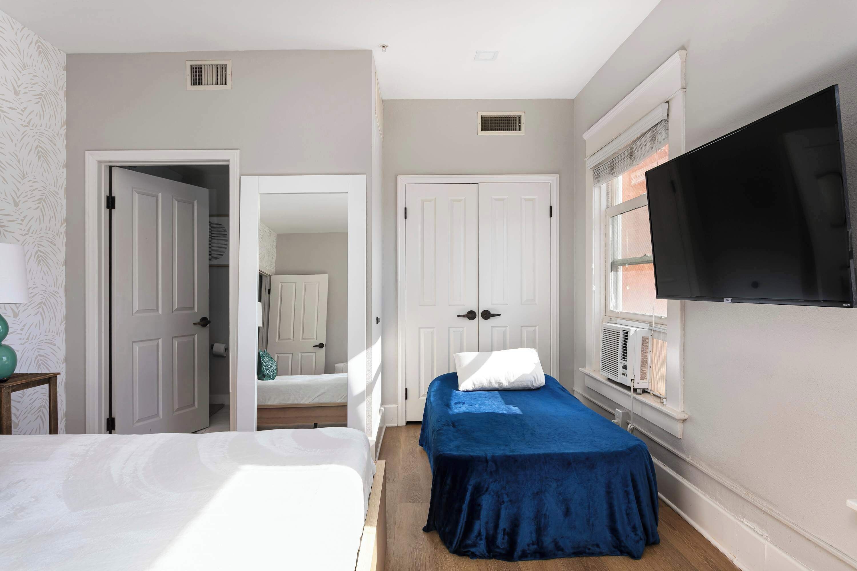 A bedroom with two beds, a TV, and a wardrobe.