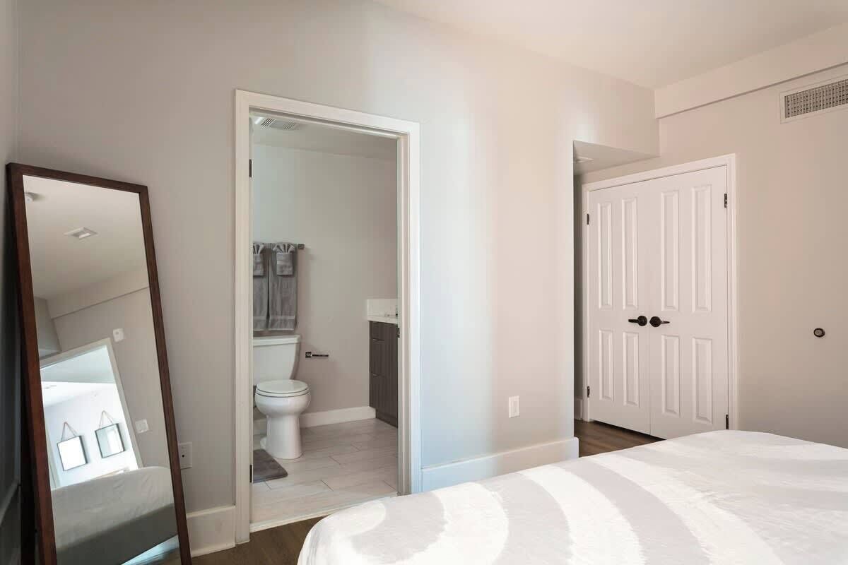 Une chambre à coucher avec un grand lit, une porte donnant sur une salle de bain et un miroir.