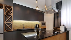 Een moderne keuken met donkere kastjes, een houten kookeiland en een ingebouwde wijnkoeler.