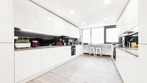 Eine moderne Küche mit weißen Schränken, einer zentralen Kochinsel und einem großen Fenster für natürliches Licht.