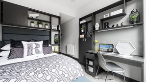 Ein modernes Schlafzimmer mit einem großen Bett, einem Schreibtisch und Regalen mit Dekoration.